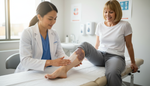Clinician applying skin moisturiser to a patient's lower leg after cellulitis as part of long-term skin protection