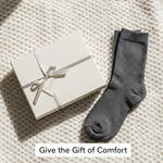 A beautifully wrapped gift box with neatly folded compression socks, symbolizing thoughtful gifting. Headline: Give the Gift of Comfort. For an article on choosing perfect compression socks as a gift.